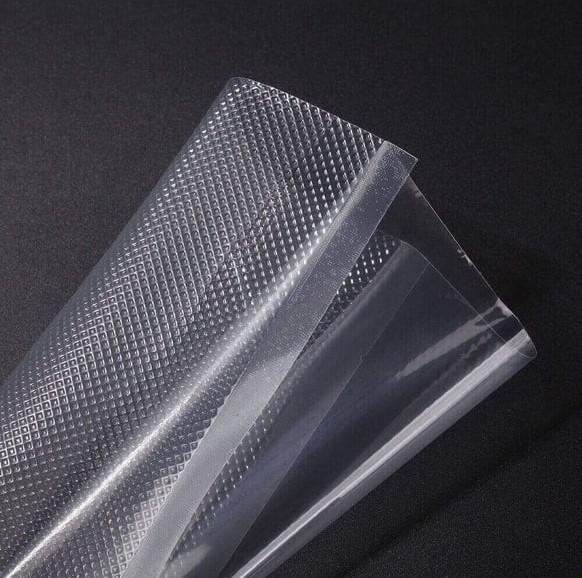 Embossed vacuum bags and a roll with a channelled surface